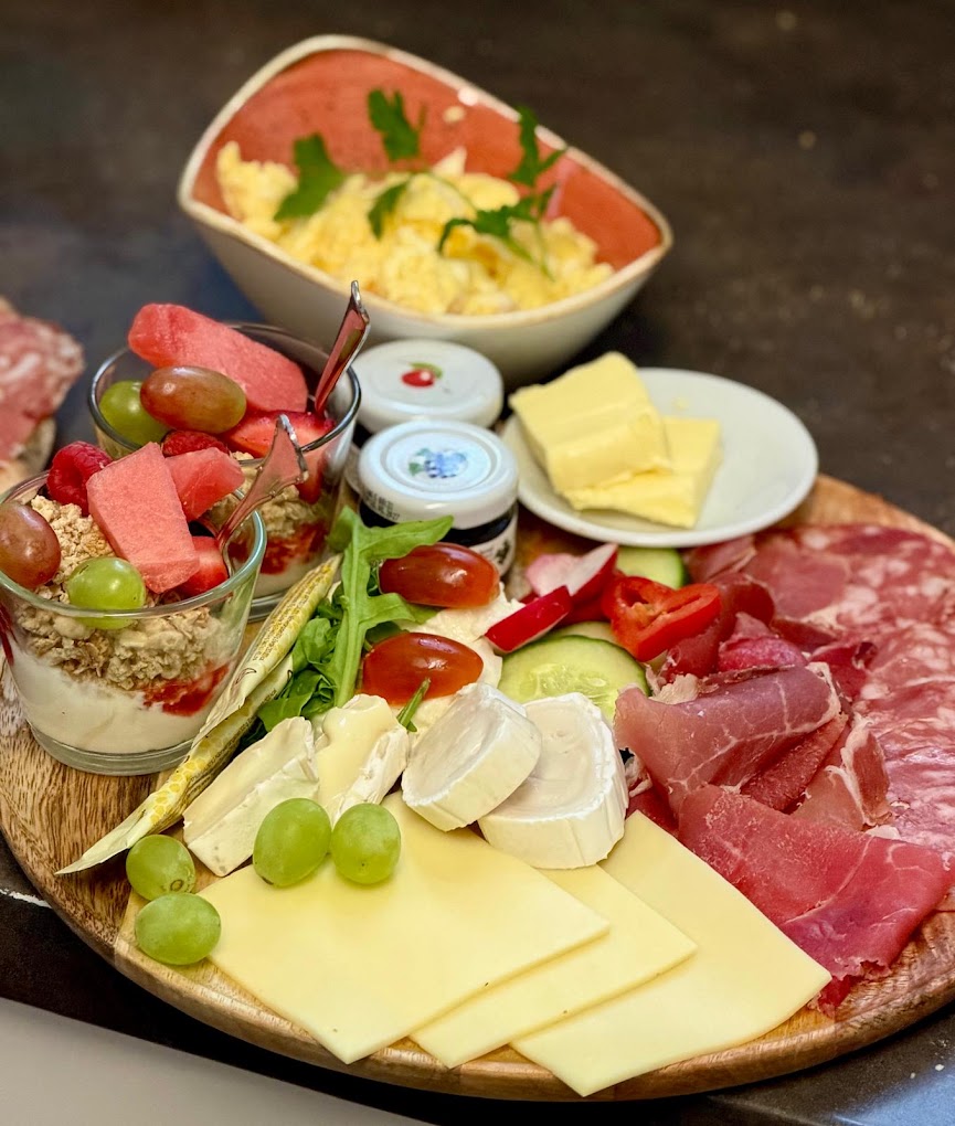 Frühstücksplatte mit Käse, Schinken, Rührei und Müsli